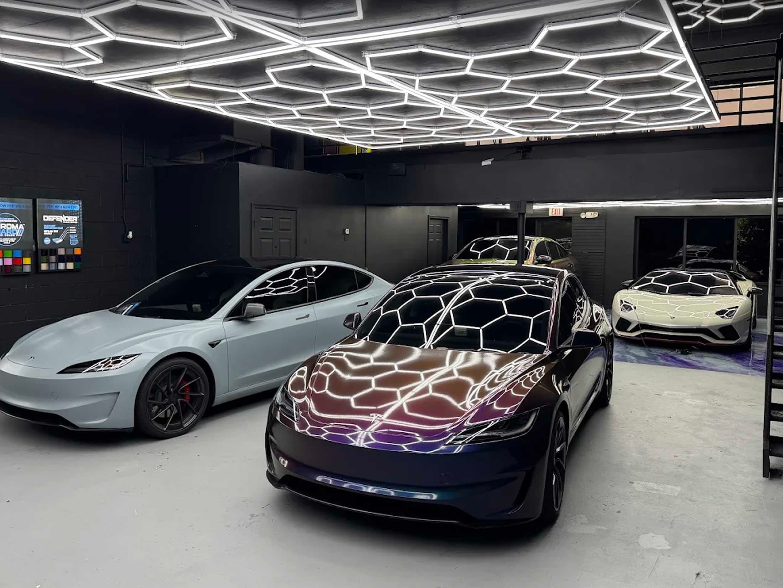 Capital Exotic Studio floor. Wrapped Teslas and a Lamborghini Aventador under honeycomb lights